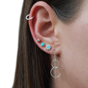 A close-up of an ear with five earrings, including hoops, studs, and 🟢 Mint Green Faux Opal Silver Stud Earrings.