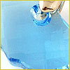 A close-up of a light blue, translucent liquid being poured from a glass container.
