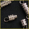 Small metallic clasps with ridged patterns are displayed on a black textured surface.