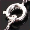 Close-up of a silver spring ring clasp attached to a chain, used for fastening jewelry, on a black background.