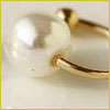 A close-up of a gold ring featuring a large white pearl as the centerpiece, set against a light background.