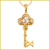 Gold key-shaped pendant with a decorative design and a small clear gem, hanging from a gold chain.
