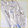 Close-up of a silver or white gold ring with intricate designs and embedded small, sparkling clear stones.