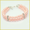 Three-strand pink pearl bracelet with silver clasps and two silver spacers on a white background.