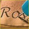 A blue pen writes the letter R on a tan surface, possibly the start of a signature or name.