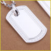 Silver dog tag pendant with a blank surface, hanging from a chain, placed on a brown background.