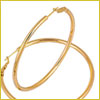 Two gold hoop earrings crossed over each other on a white background.