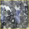 Small, irregularly shaped tanzanite gemstones in various shades of blue and gray are clustered together against a white background.