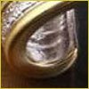 A close-up of a metallic gold and silver decorative object with intricate engraved patterns and a curved edge.