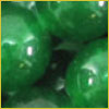 Several shiny green gumballs closely packed together, showing their smooth, glossy surfaces.