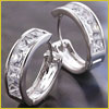 A pair of silver hoop earrings with embedded square-cut clear gemstones displayed on a dark surface.
