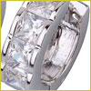Close-up of a silver ring with several square-cut clear gemstones set in a row along its band.