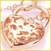 Gold heart-shaped pendant with intricate cutout design on a matching gold chain, shown in close-up.