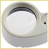 A round magnifying glass with a white plastic frame, viewed from above on a white background.