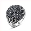 Silver ring with a cluster of dark stones on top, featuring an intricate, swirling design on the sides.
