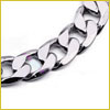 Close-up of a silver curb chain bracelet with interlocking, flat, and wide links on a white background.