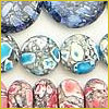 Colorful round and oval beads with marbled blue, gray, and pink patterns arranged in rows on a light background.