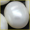 A close-up of a shiny white pearl with a smooth, oval surface, surrounded by parts of other pearls.