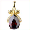 Gold pendant with a bow design, featuring a large, faceted dark red gemstone in a teardrop shape.