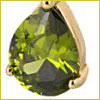 Close-up of a faceted, teardrop-shaped green gemstone set in a gold prong setting.