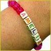 A pink beaded bracelet on a wrist with letter beads spelling AMELIA..