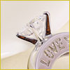 A close-up of a diamond ring with the word LOVE engraved on the metal band.