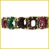 A gold bracelet with rectangular red, green, and purple gemstones set in a row.