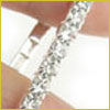 A close-up of a hand holding a thin, diamond-studded ring against a white background.
