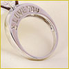 A silver ring with the words I LOVE YOU engraved on it, resting on a light-colored surface.