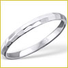 A thin, polished silver ring with a smooth and slightly faceted surface, displayed on a white background.