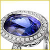 Silver ring with a large oval blue gemstone surrounded by small clear stones on a white background.