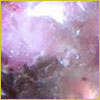Close-up of a shiny, purple and pink mineral or gemstone surface with a reflective, smooth texture.