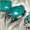 Close-up of a polished turquoise stone set in an ornate silver ring with a leaf-like design.